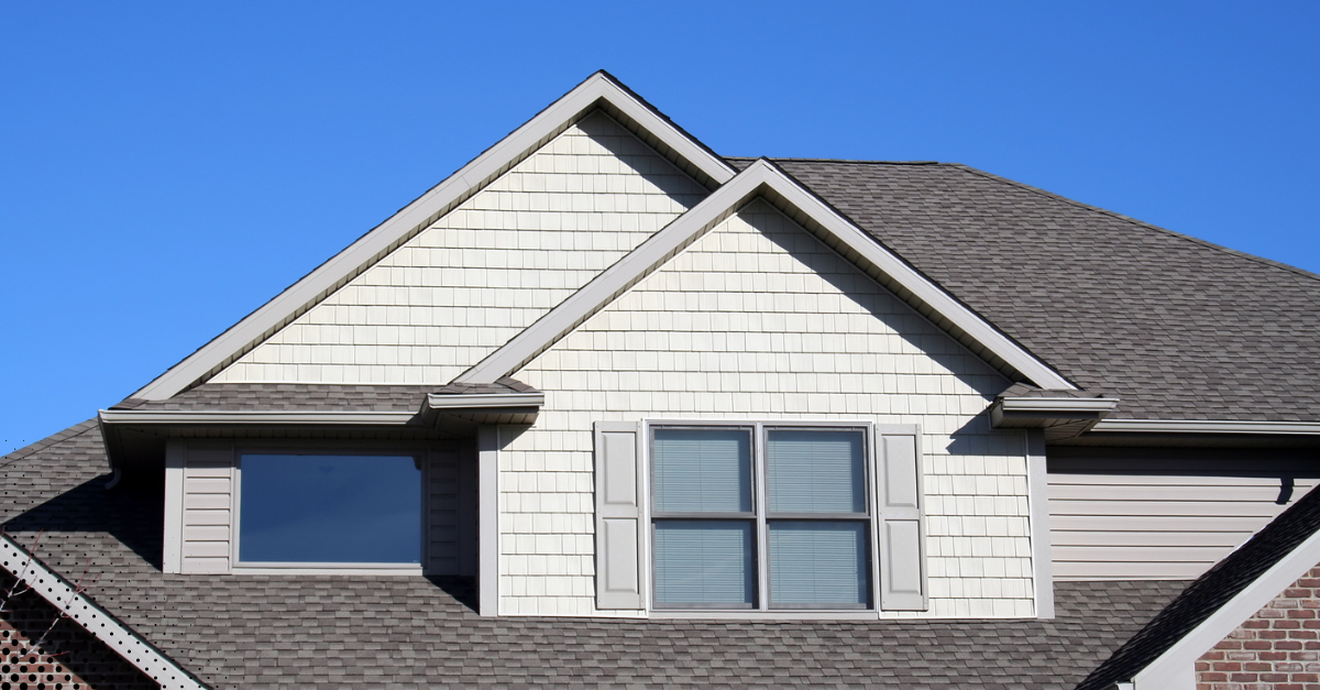 Close-up of a home’s exterior gable and roof, highlighting the siding and shingle condition