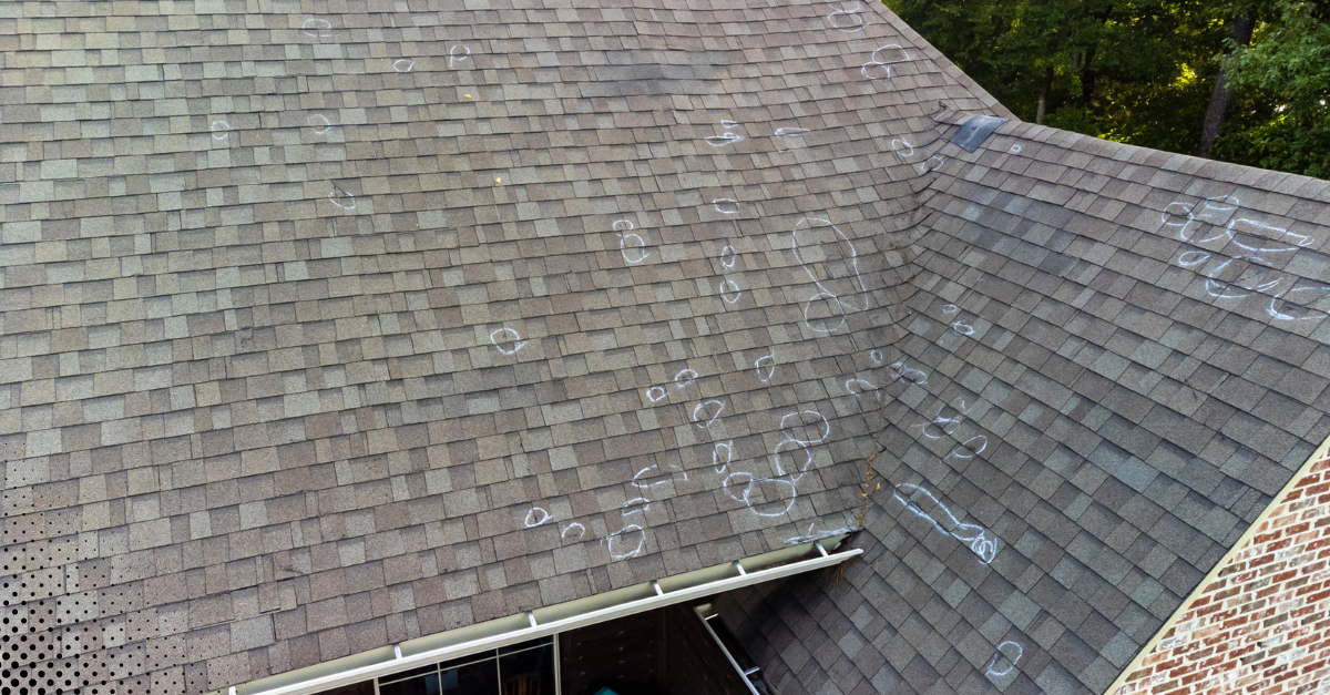 Hail-damaged asphalt shingle roof with chalk markings identifying impact spots