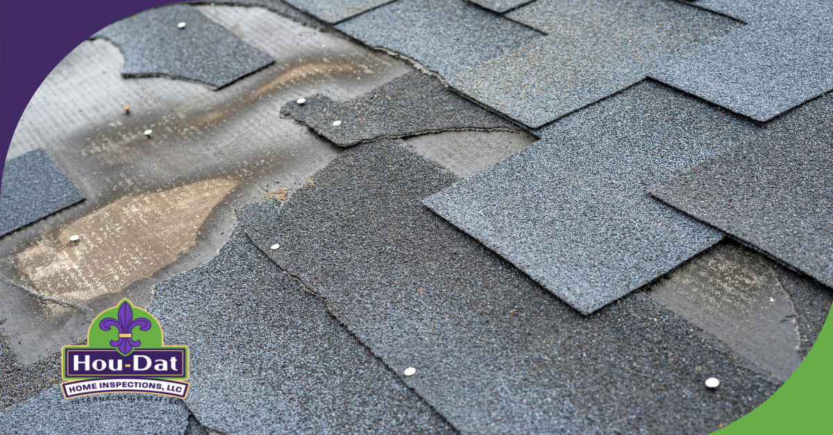 Close-up of damaged shingles on a roof with exposed underlayment and nails.