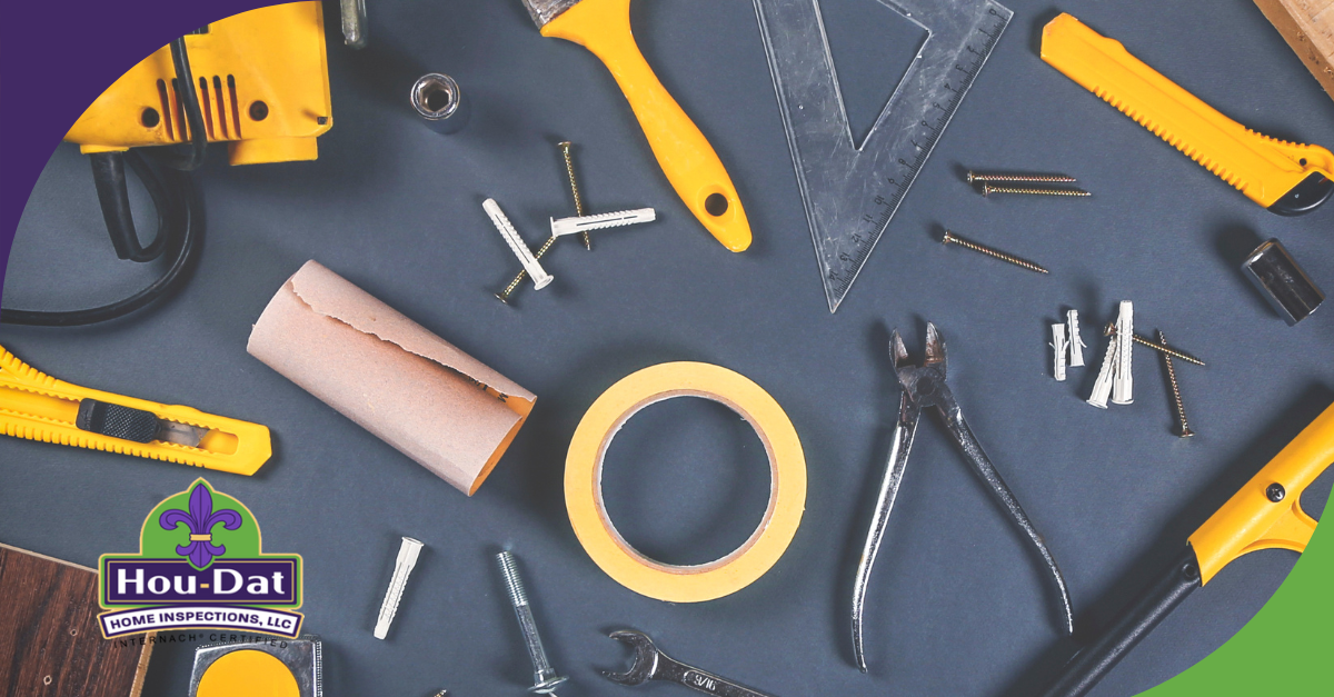 Various hand tools and fasteners arranged on a dark surface for home repair or inspection.